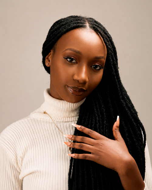 Woman with braided hair wearing a white turtleneck sweater against a beige background